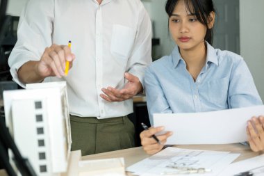 İki erkek ve kadın mühendis ya da mimar ofis işyerinde birlikte çalışarak inşaat projesinin planları ve planları için model arıyorlar..