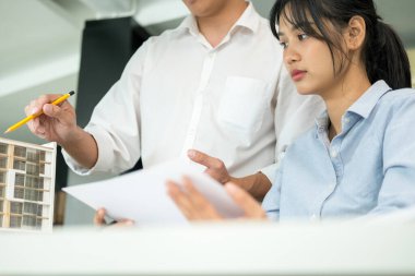 İki erkek ve kadın mühendis ya da mimar ofis işyerinde birlikte çalışarak inşaat projesinin planları ve planları için model arıyorlar..