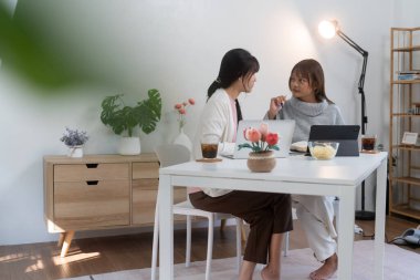 Evde dizüstü bilgisayar kullanan ve kitap okuyan kız öğrenci, İnternet üzerinden öğrenim.