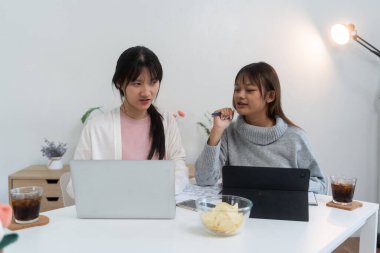 Evde dizüstü bilgisayar kullanan ve kitap okuyan kız öğrenci, İnternet üzerinden öğrenim.