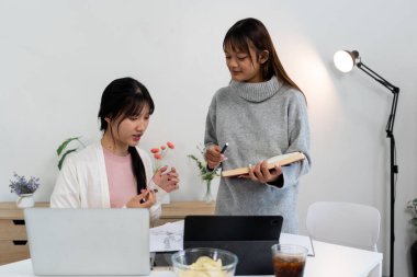 Evde dizüstü bilgisayar kullanan ve kitap okuyan kız öğrenci, İnternet üzerinden öğrenim.