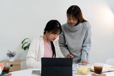 Evde dizüstü bilgisayar kullanan ve kitap okuyan kız öğrenci, İnternet üzerinden öğrenim.