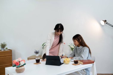 Evde dizüstü bilgisayar kullanan ve kitap okuyan kız öğrenci, İnternet üzerinden öğrenim.