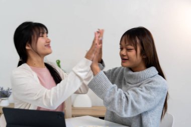 Evde dizüstü bilgisayar kullanan ve kitap okuyan kız öğrenci, İnternet üzerinden öğrenim.