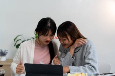 Evde dizüstü bilgisayar kullanan ve kitap okuyan kız öğrenci, İnternet üzerinden öğrenim.