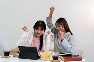 Evde dizüstü bilgisayar kullanan ve kitap okuyan kız öğrenci, İnternet üzerinden öğrenim.