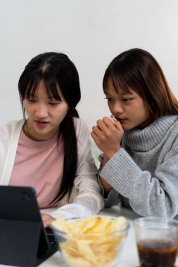 Evde dizüstü bilgisayar kullanan ve kitap okuyan kız öğrenci, İnternet üzerinden öğrenim.