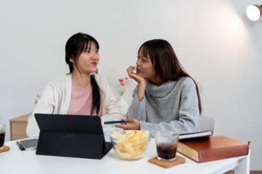 Evde dizüstü bilgisayar kullanan ve kitap okuyan kız öğrenci, İnternet üzerinden öğrenim.