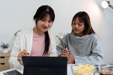 Evde dizüstü bilgisayar kullanan ve kitap okuyan kız öğrenci, İnternet üzerinden öğrenim.