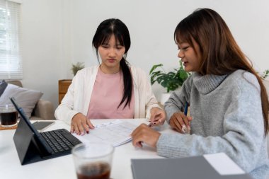 Evde dizüstü bilgisayar kullanan ve kitap okuyan kız öğrenci, İnternet üzerinden öğrenim.