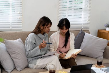 Evde dizüstü bilgisayar kullanan ve kitap okuyan kız öğrenci, İnternet üzerinden öğrenim.