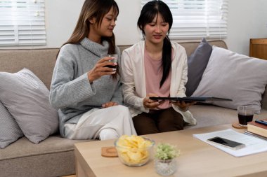 Evde dizüstü bilgisayar kullanan ve kitap okuyan kız öğrenci, İnternet üzerinden öğrenim.
