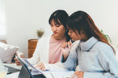 Evde dizüstü bilgisayar kullanan ve kitap okuyan kız öğrenci, İnternet üzerinden öğrenim.