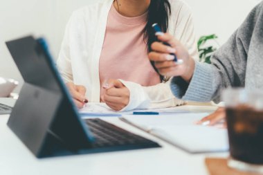 Evde dizüstü bilgisayar kullanan ve kitap okuyan kız öğrenci, İnternet üzerinden öğrenim.