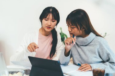 Evde dizüstü bilgisayar kullanan ve kitap okuyan kız öğrenci, İnternet üzerinden öğrenim.