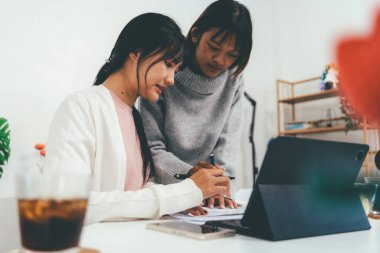 Evde dizüstü bilgisayar kullanan ve kitap okuyan kız öğrenci, İnternet üzerinden öğrenim.