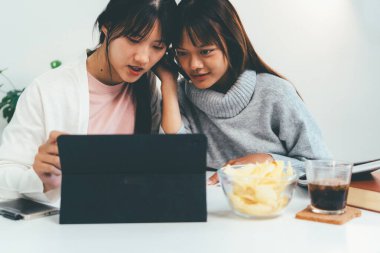 Evde dizüstü bilgisayar kullanan ve kitap okuyan kız öğrenci, İnternet üzerinden öğrenim.