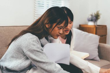 Evde dizüstü bilgisayar kullanan ve kitap okuyan kız öğrenci, İnternet üzerinden öğrenim.