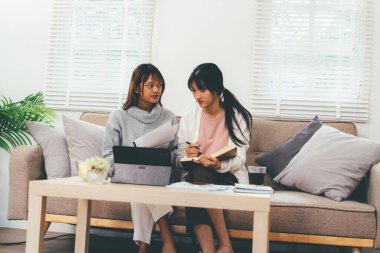 Evde dizüstü bilgisayar kullanan ve kitap okuyan kız öğrenci, İnternet üzerinden öğrenim.