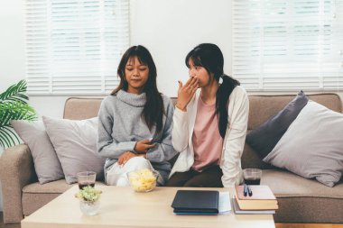 Evde dizüstü bilgisayar kullanan ve kitap okuyan kız öğrenci, İnternet üzerinden öğrenim.