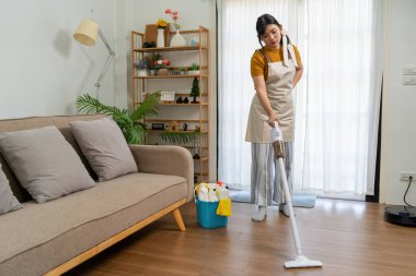 Genç modern Asyalı kadın evde temizlik yapıyor. Kendinden emin.