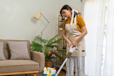 Genç modern Asyalı kadın evde temizlik yapıyor. Kendinden emin.