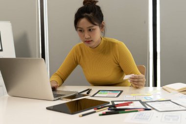 Modern bir çalışma alanında yaratıcı web tasarımcısı beyin fırtınası uygulaması arayüzü ve dijital şablonlar tasarlıyor. Profesyonel bir teknoloji ortamında UX / UI geliştirme süreci.