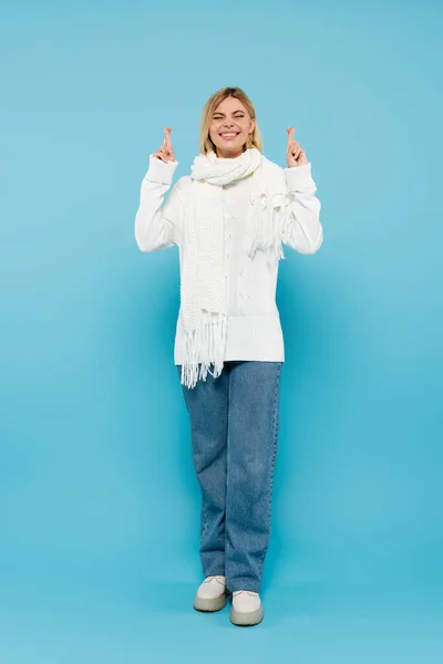 満面の笑みを浮かべてブロンド女性で白いセーターとスカーフ交差指で青 — ストック写真