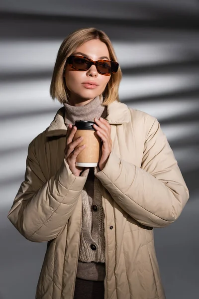Młoda Kobieta Beżowej Kurtce Zimowej Okularach Przeciwsłonecznych Trzyma Papierowy Kubek — Zdjęcie stockowe