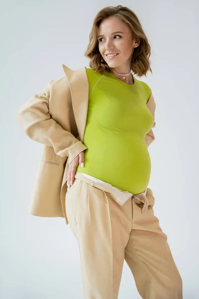 즐거운 임신중인 회색에서 고립된 포즈를 취하고 바라봅니다 — 스톡 사진