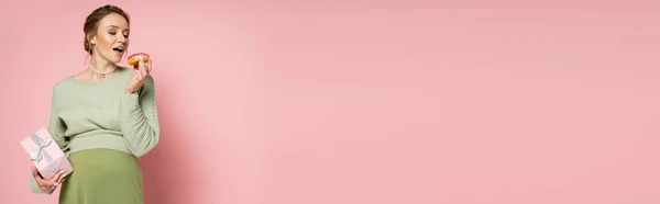 Вагітна Жінка Відкритим Ротом Тримає Пончик Подарункову Коробку Рожевому Фоні — стокове фото