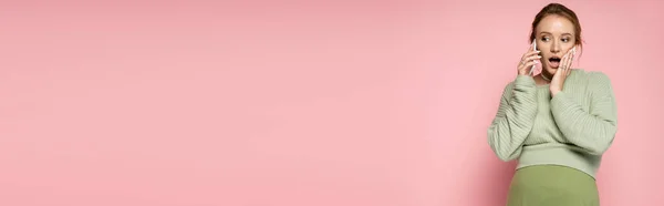 Шокированная Беременная Женщина Свитере Разговаривает Мобильному Телефону Розовом Фоне Баннер — стоковое фото