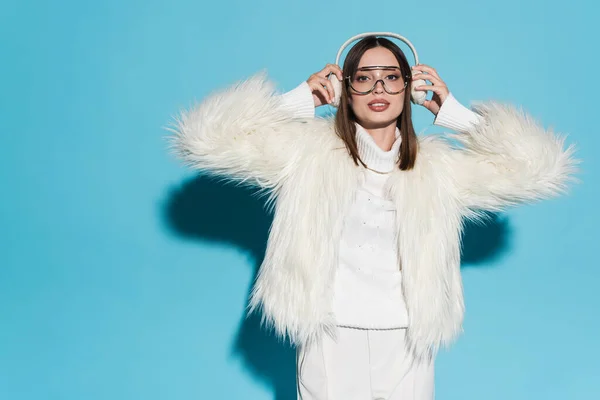 Stylish Young Woman Eyeglasses Faux Fur Jacket Holding Winter Earmuffs — Stock Photo, Image