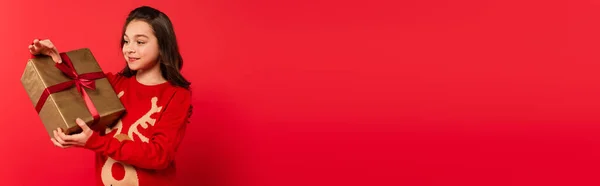 Щаслива Дитина Язаному Светрі Дивлячись Загорнутий Різдвяний Подарунок Червоному Банер — стокове фото