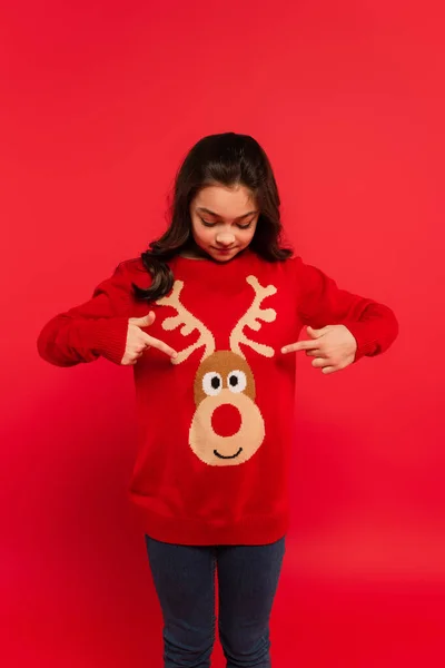 크리스마스 스웨터를 손가락으로 가리키며 소녀붉은 — 스톡 사진
