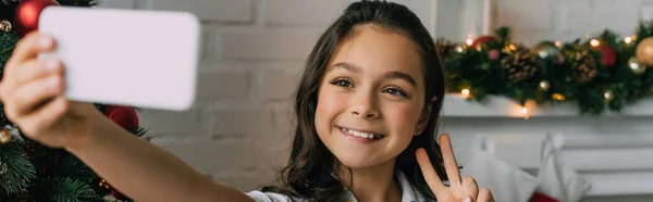 Pozytywne Dziecko Pokazuje Znak Pokoju Podczas Robienia Selfie Podczas Świąt — Zdjęcie stockowe