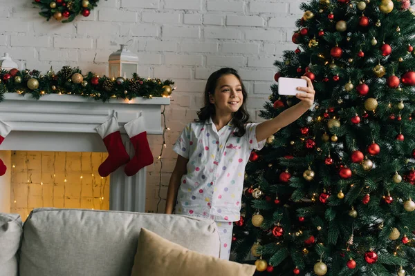 Chica Pijama Tomando Selfie Teléfono Inteligente Cerca Chimenea Árbol Navidad —  Fotos de Stock