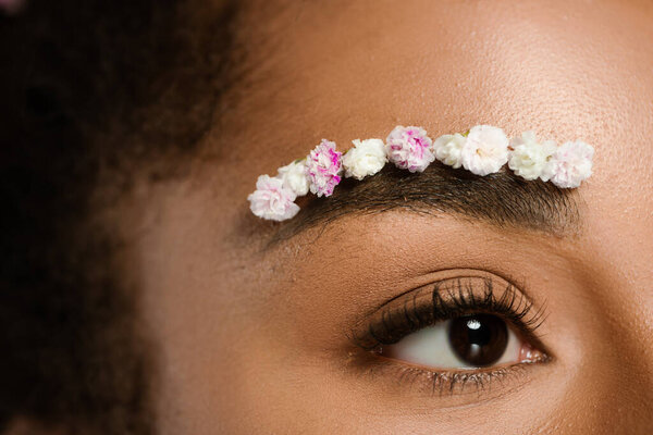 cropped view of african american woman with flowers on eyebrow 