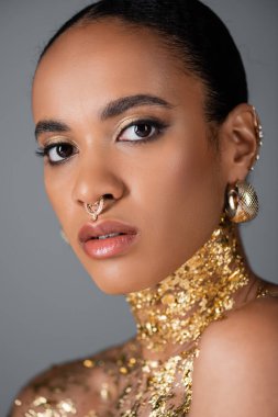 Güzel Afro-Amerikan modelinin portresi. Göğsünde folyo ve gri üzerinde piercing var. 