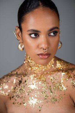Modayı takip eden Afro-Amerikan modelinin portresi. Aksesuarları ve altın folyolar gri üzerine izole edilmiş. 