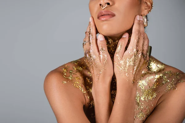 stock image Cropped view of african american woman with golden foil on body touching face isolated on grey 