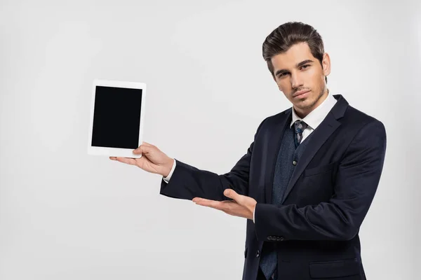 スーツ姿のビジネスマンがグレーで隔絶された空白の画面でデジタルタブレットを持ち — ストック写真