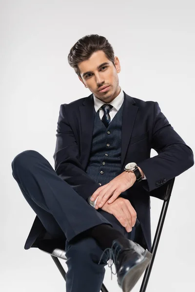 灰色で隔離されたふりをしながら椅子に座る正式な服装のビジネスマン — ストック写真