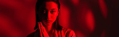 Asyalı bir kadının portresi dua eden elleri ile arka plandaki kameraya bakıyor. Kırmızı ışık, pankart.