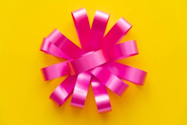 Sarı arkaplanda pembe hediye yayının üst görünümü 