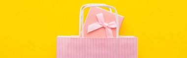 Top view of pink present and striped shopping bag on yellow background, banner  clipart