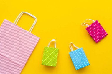Sarı arkaplanda renkli alışveriş torbalarının üst görüntüsü 
