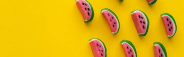 Sarı arka planda karpuz şeklinde lezzetli şekerlerin üst görüntüsü, afiş 