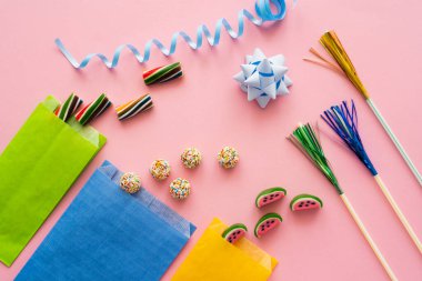 Top view of candies near paper bags and serpentine on pink background  clipart