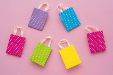 Pembe arka planda küçük renkli alışveriş çantalarının üst görüntüsü 